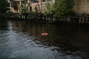 red boat on water near green trees