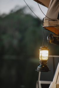 retro lamp hanging from tent during camping in nature in evening